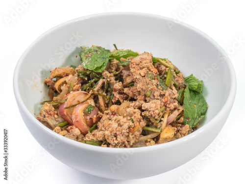 The close up of Spicy minced pork salad in white bowl on white table.