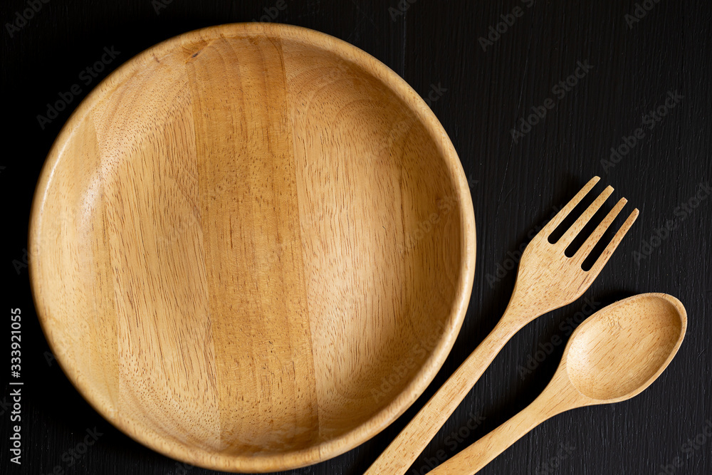 Spoons, forks and Dish made of wood on the black wooden background Spoons, forks and Dish made of wood on the black wooden background