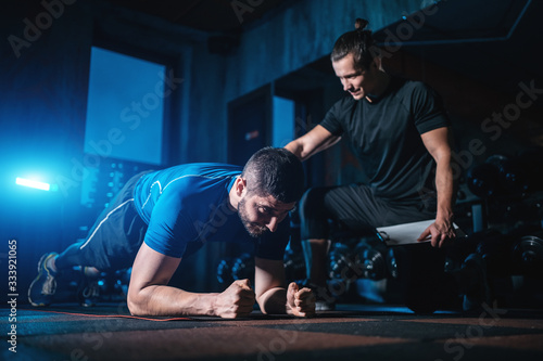 Foto young man has workout with personal trainer in modern gym