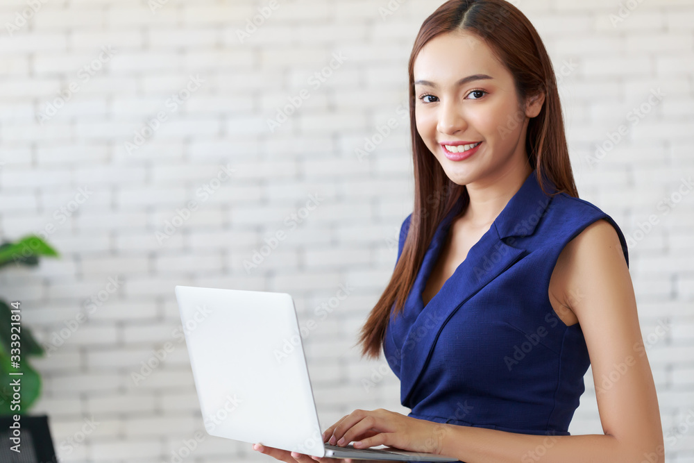 Young happy beauty Asian woman holding the laptop making a research in the office. Young happy beauty Asian woman holding the laptop making a research in the office.
