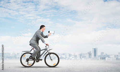 Businessman with megaphone on bike
