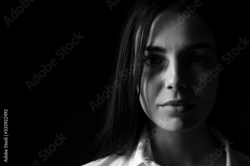 Black and white portrait of scared female victim on dark background. Concept of violence