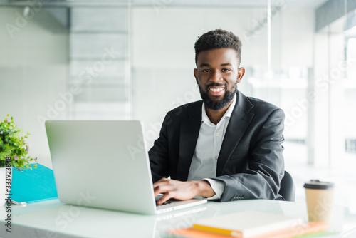Portrait of handsome African black young business man working on laptop at office desk