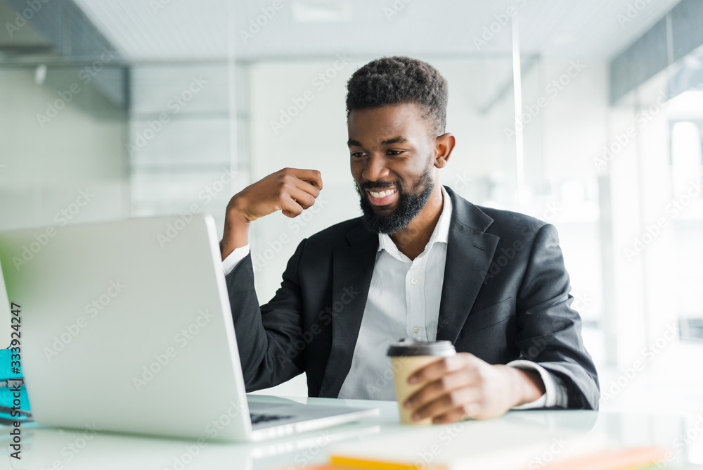 Young African American manager with stubble sitting in front of open laptop wearing earphones while having video conference call with business partners Young African American manager with stubble sitting in front of open laptop wearing earphones while having video conference call with business partners