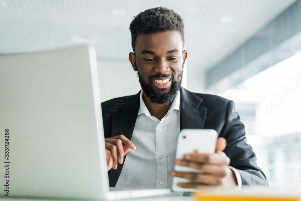 Young african american business man using phone and making winner gesture with fist in office Young african american business man using phone and making winner gesture with fist in office