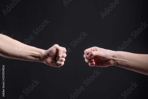 Men's hands on a dark background, show a game of stone, scissors, paper. The concept of confrontation and rivalry, games