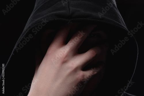 Fotografia A man in a black hood on a black background, studio photography