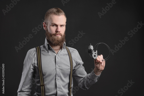 Handsome young man presents car parts on a gray background. The concept of sales and testing of goods