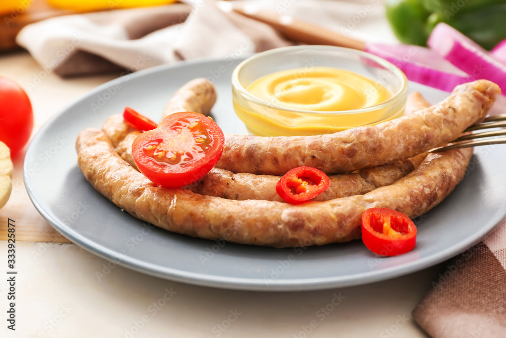 Plate with tasty grilled sausages and sauce on table Plate with tasty grilled sausages and sauce on table