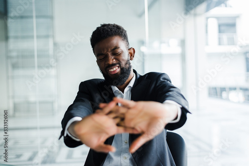 African businessman take break during workday stretching hands fingers starting office work