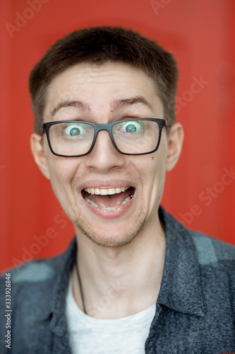 portrait of a cute guy with very bright facial expressions and emotions against a red wall