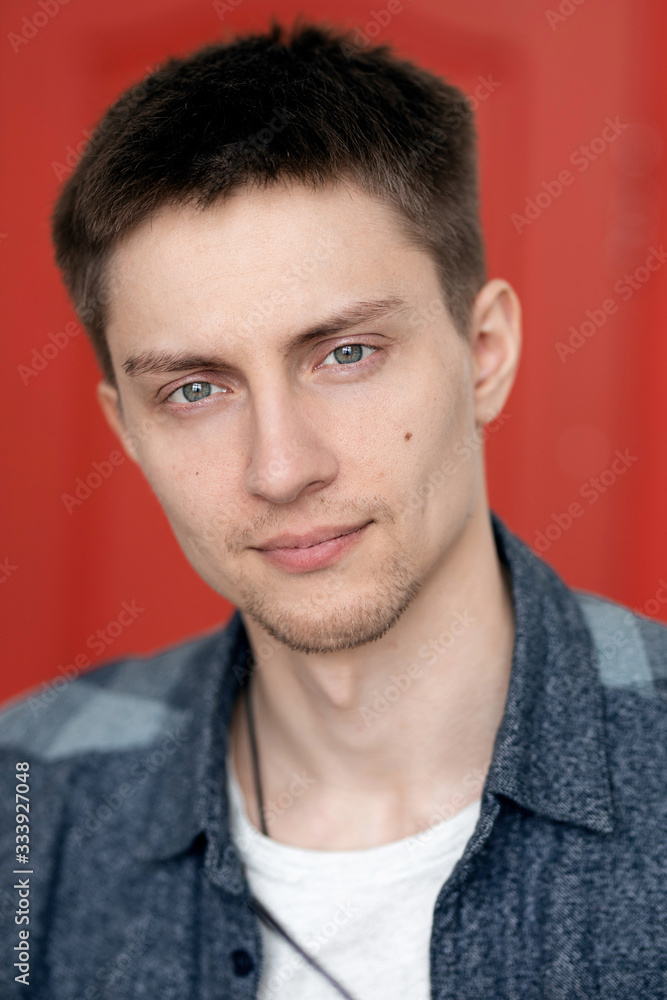 portrait of a cute guy with very bright facial expressions and emotions against a red wall portrait of a cute guy with very bright facial expressions and emotions against a red wall