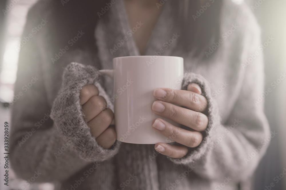 The girl holding the mug of hot coffee in her tender hand. in the morning soft sunlight. The girl holding the mug of hot coffee in her tender hand. in the morning soft sunlight.