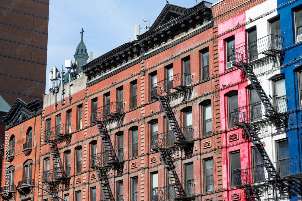 Row of Old Colorful Brick Residential Buildings in Hell's Kitchen of New York City with Fire Escapes