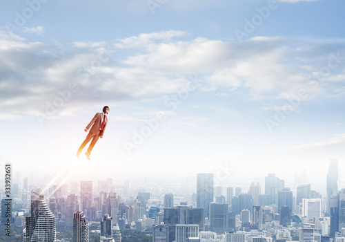 Businessman in suit and aviator hat flying in sky