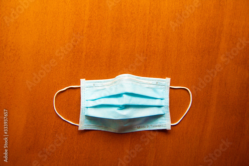 Close up medical face mask on wooden table background, Selective focus to green face mask on wood background.