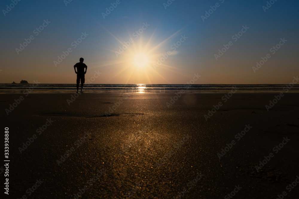 silhouette of a man standing on the beach at sunset