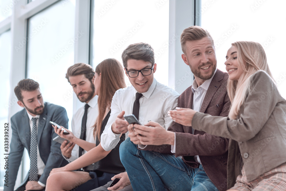 young employees using their smartphones to view the news online young employees using their smartphones to view the news online