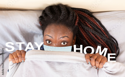 Self-isolation during virus outbreak. African American woman with mask under blanket and phrase STAY HOME, collage photo