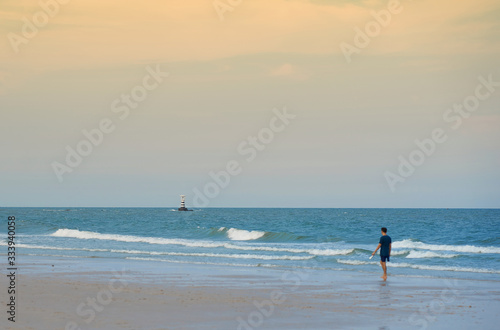 blur unidentified person walking along coast line on sea waves and blue sky background in beach summer concept