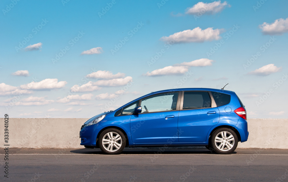 Blue car parked on the road against the background of the sunny sky. Automotive photography. Space for text. Background with car.