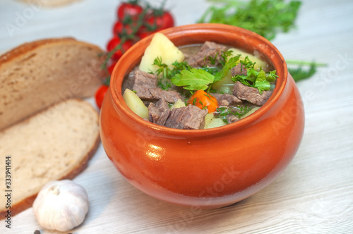 Roast in a pot with beef meat and potatoes on the table