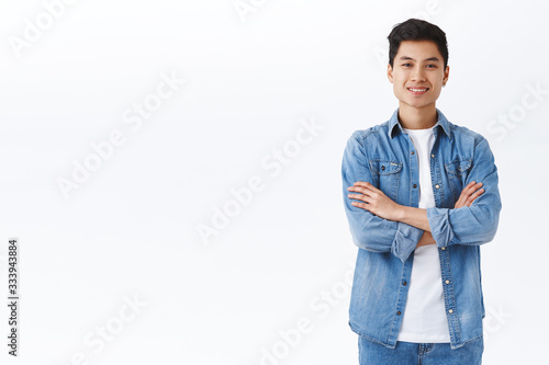 Career, employement and young people concept. Handsome enthusiastic chinese man cross hands over chest and smiling pleased, looking satisfied, ready to apply for job, good candidate photo