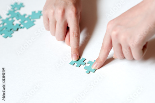 two hands holding puzzle pieces on a white background