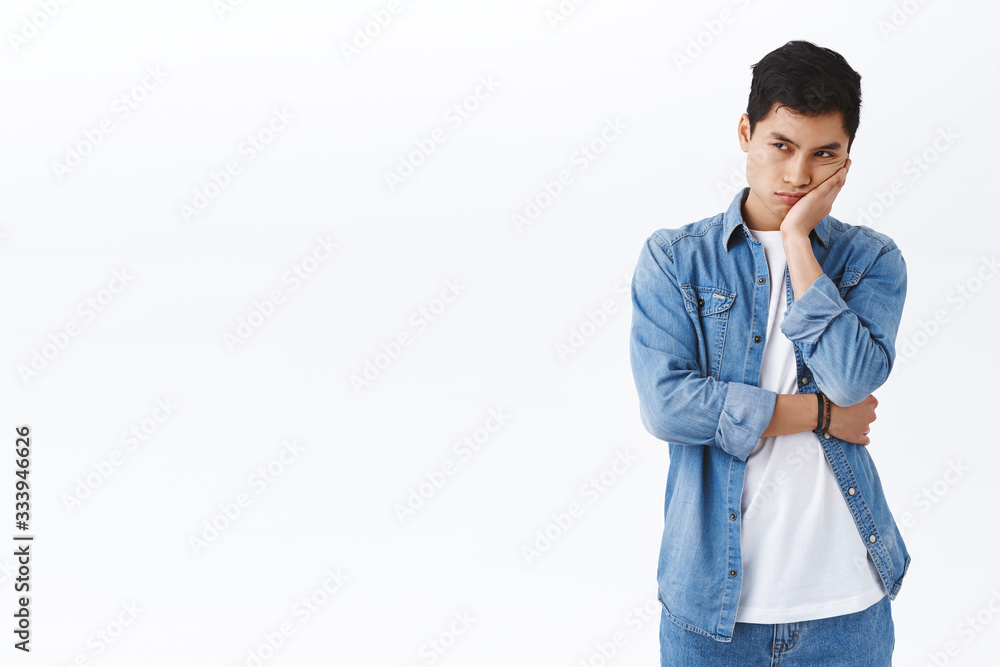 Portrait of angry and displeased young asian guy, sulking, lean on palm and peeking annoyed at something, being envy about person having cool new game platform, express jealousy or irritation Portrait of angry and displeased young asian guy, sulking, lean on palm and peeking annoyed at something, being envy about person having cool new game platform, express jealousy or irritation