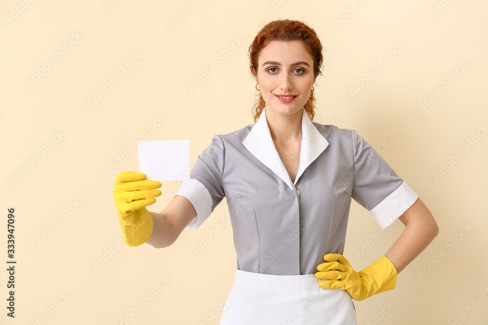 Beautiful young chambermaid with business card on color background Beautiful young chambermaid with business card on color background
