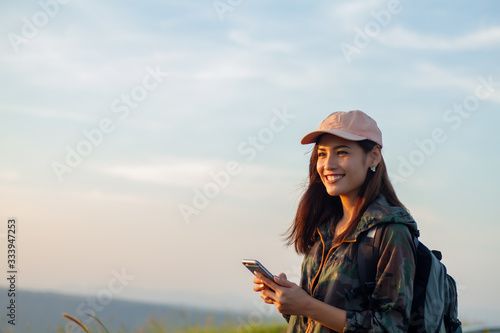 women asian with bright backpack looking at a map. View from back of the tourist traveler on background mountain, Female hands using smartphone,