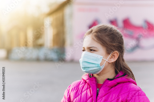 Sad, depressed little girl in sterile medical protective from virus mask outdoors. Health care, epidemic, pandemic, illness concept © Andreshkova Nastya