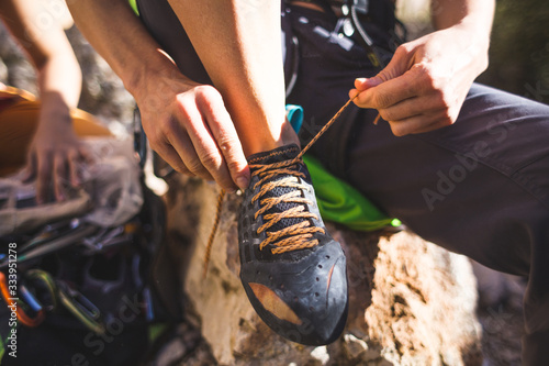 Rock climber puts on climbing shoes and ties shoelaces.