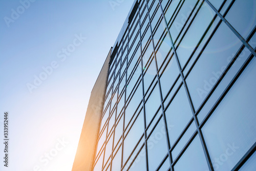 Facade of modern glass building at sunset. Warm and cool tone contrast. Sun flare.