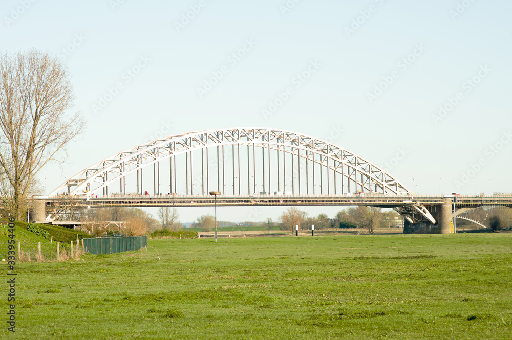 Waalbrug over the river the Waal, with in the foreground a meadow in Nijmegen, Netherlands Waalbrug over the river the Waal, with in the foreground a meadow in Nijmegen, Netherlands