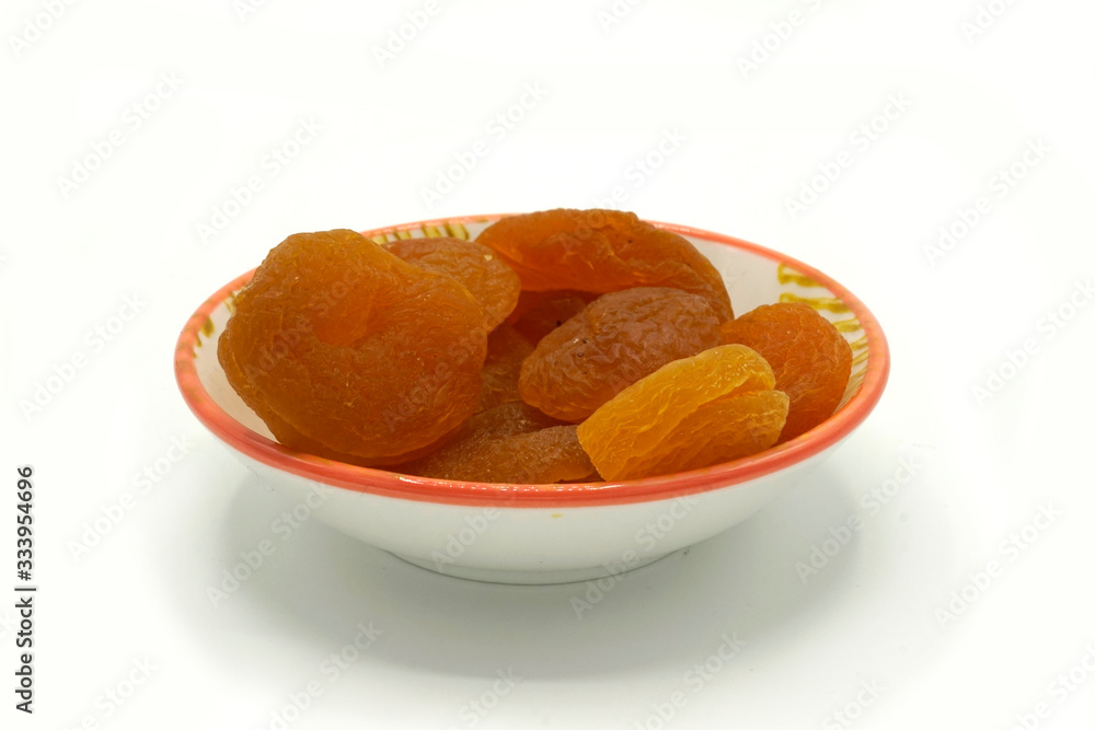 Dried apricots on a ceramic saucer isolated on white background. Energy and fiber natural source. Dieting food. Dried apricots on a ceramic saucer isolated on white background. Energy and fiber natural source. Dieting food.