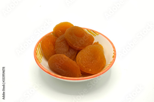 Dried apricots on a ceramic saucer isolated on white background. Energy and fiber natural source. Dieting food. photo