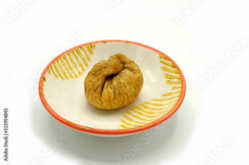 Dried figs on a ceramic saucer isolated on white background. Energy and fiber natural source. Dieting food. photo