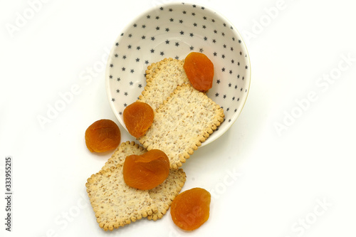 Dried fruits and digestive biscuits on a ceramic saucer isolated on white background. Energy and fiber natural source. Dieting food. photo