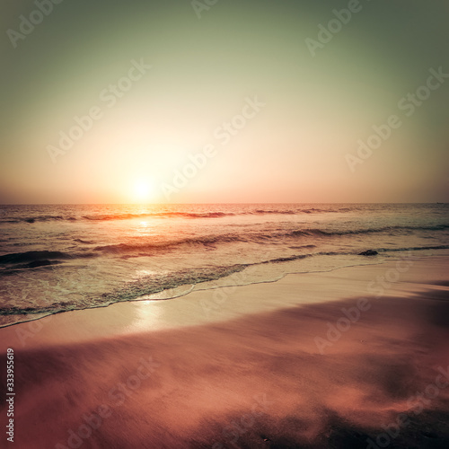 Beautiful sunset at tropical beach. Ocean sandy coast under evening sun. South India landscape in vintage style