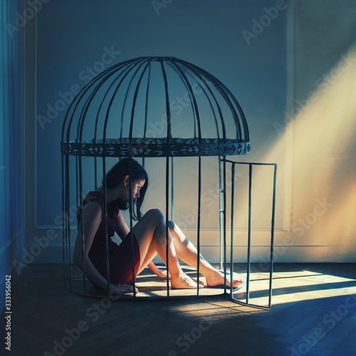 Young woman sitting in cage photo