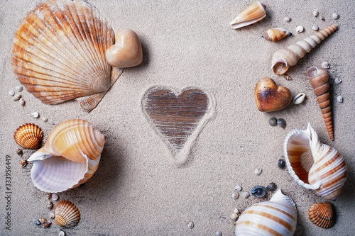Shells, sand and heart of stone on a wooden table. Symbol "Heart" painted on sand. Layout for design. © VLADISLAV