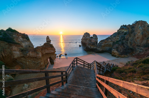 Praia do Camilo at sunrise with wooden staircase in foreground