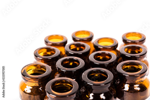 Many empty brown glass medical bottles isolated on a white background. The course of treatment is completed. Mass vaccination. Capacities for tablets. Production of containers.