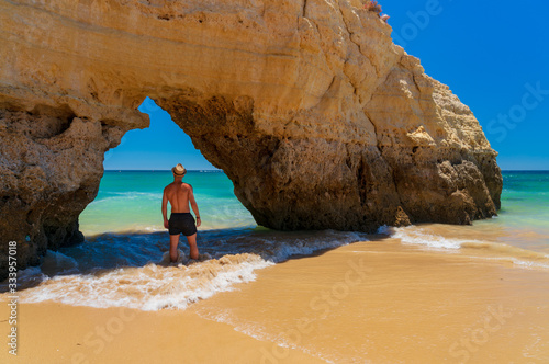 Man with hat looking at sea in natural arch