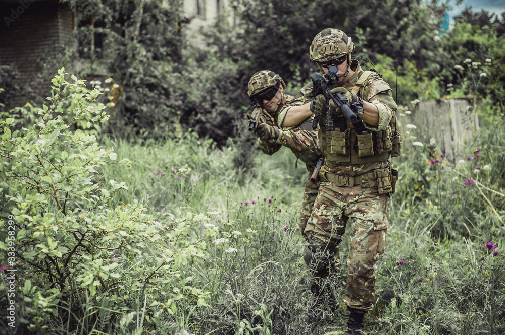 Two men in military camouflage vegetato uniforms with automatic assault rifles