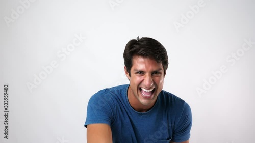 Handsome young man laughing a lot when he see some joke or Handsome young guy sneering someone and pointing finger to someone. Attractive man can not stop laughing. He gibe something that amusing.  photo