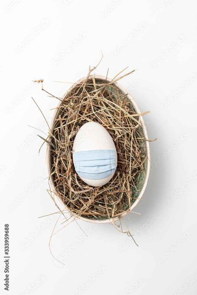 Osterei mit Mundschutz im Nest auf weißem Hintergrund Osterei mit Mundschutz im Nest auf weißem Hintergrund