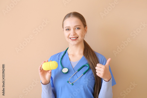 Doctor with pills box showing thumb-up on color background