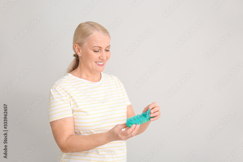 Mature woman with pills box on light background Mature woman with pills box on light background